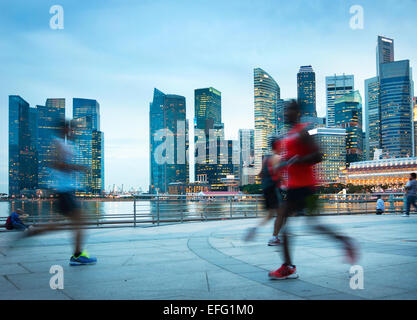 Menschen Joggen in der Dämmerung in Singapur. Singapur Downtown Core im Hintergrund Stockfoto