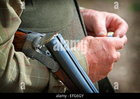 Mann Spiel Schießen mit Gewehr und Pistole der Entladerohrhalterung Patronen, Nahaufnahme 7/8 Stockfoto