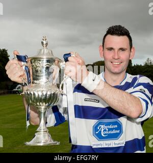 Newtonmore Kapitän Scott Chisholm mit dem Cup nach einem Sieg über Kyles Athletic in der MacAulay-Cup-Finale 2014 bei Mossfield, Oban. Stockfoto