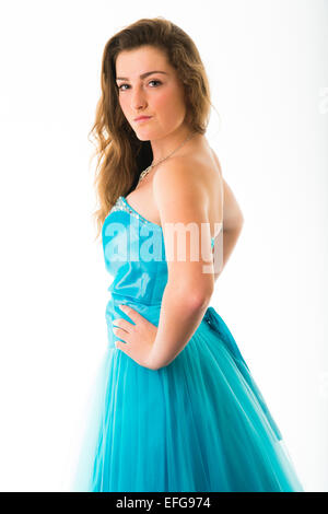 Ein anmutig elegant schlank zuversichtlich 14 14 jährige Teenager-Mädchen Modell mit langen braunen Haaren, stehend mit den Händen an den Hüften tragen eine blaue Kugel Kleid Party Kleid Kleid Kleid posiert in einem Studio UK Stockfoto