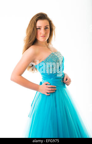 Ein anmutig elegant schlank zuversichtlich 14 14 jährige Teenager-Mädchen Modell mit langen braunen Haaren, stehend mit den Händen an den Hüften tragen eine blaue Kugel Kleid Party Kleid Kleid Kleid posiert in einem Studio UK Stockfoto