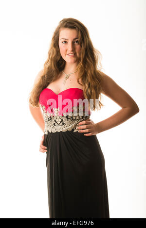 Ein anmutig elegant schlank zuversichtlich 14 14 jährige Teenager-Mädchen Modell mit langen braunen Haaren, stehend mit den Händen an den Hüften tragen eine Kleid Kleid posiert in einem Studio UK Stockfoto