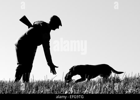Wildhüter mit gun Hund im Feld abrufen Spiel Bird, Schwarze & Weiße Silhouette Stockfoto