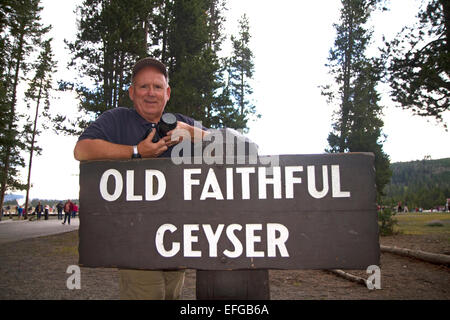 David R. Frazier stehen bei den Anzeichen für Old Faithful Geysir im Yellowstone-Nationalpark, Wyoming, USA. Stockfoto