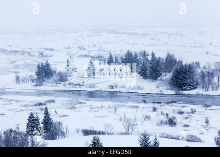 Panoramaaussicht über den gefrorenen Thingvellir National Park rift valley von der Informationszentrale im Winter bei Schneesturm mit Häusern und Kirche Stockfoto