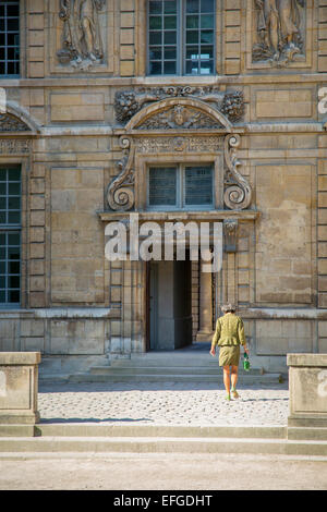 Frau zu Fuß durch Hof in Richtung Tür, Hotel de Sully, le Marais, Paris, Frankreich Stockfoto