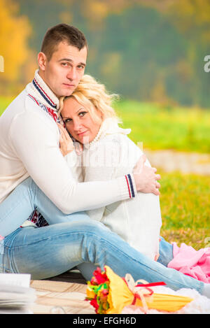 Porträt von einem liebenden paar umarmt sitzen im park Stockfoto