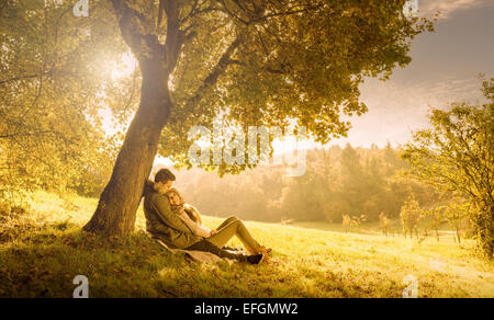 Liebespaar unter einem großen Baum im Park im Herbst Stockfoto