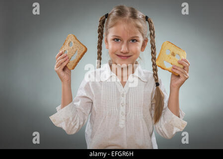 Wunderschönes kleines Mädchen mit einem glücklich Brot in einer Hand und die andere Hand hält ein trauriges Stück Brot Stockfoto