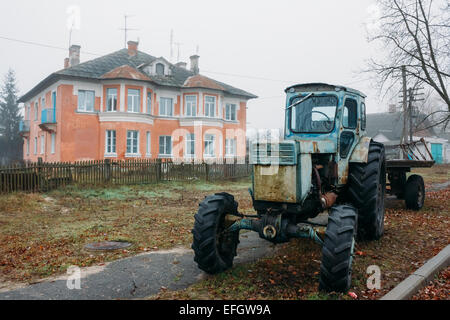 Alten sowjetischen rostigen Ackerschlepper Parken auf dem Bürgersteig in der Nähe von rotem Backstein-Haus in Dobrush, Region Gomel, Weißrussland Stockfoto