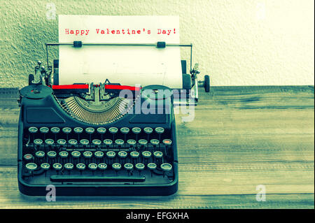 Schreibmaschine mit weißem Papierseite auf Holztisch. Probieren Sie Text Happy Valentinstag! Vintage-Stil getönten Bild Stockfoto