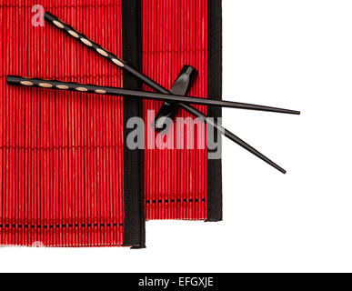 schwarzen chinesischen Stäbchen auf roten Bambusmatte. asiatischen Stil Tabelle Gedeck Stockfoto