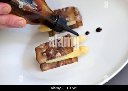 Koch, Soße auf Speck und Spargel Stockfoto