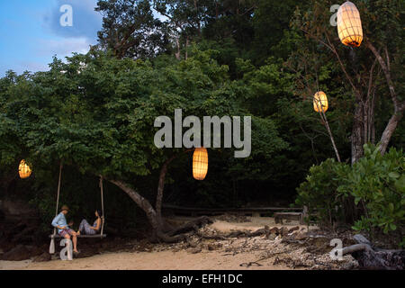 Ein paar in einer romantischen Schaukel am Strand von Six Senses Resort, Koh Yao Noi Bucht von Phang Nga, Thailand, Asien. Six Senses Yao Noi s Stockfoto