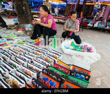 Zwei Lao Frauen verkaufen schöne handgefertigte Handtasche in Luang Prabang Straßenmarkt. Stockfoto