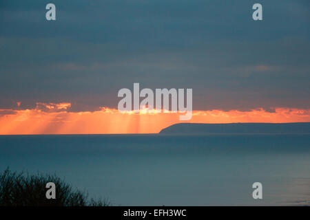 Hastings, East Sussex, England, UK. Die dramatischen winter Sonnenuntergang Blick von Hastings wie die Sonne über dem Meer und ferne Beachy Head sets. Stockfoto