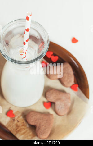 Flasche Milch mit zwei Strohhalmen und Herz Form Schokolade Cookies, selektiven Fokus Stockfoto