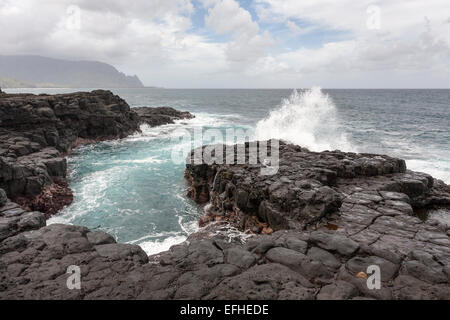 Eine kleine Coastal Einlass zu rauh zum Baden. Eine Welle stürzt gegen die Felsen in der Nähe einer kleinen Bucht in der black Rock. Stockfoto