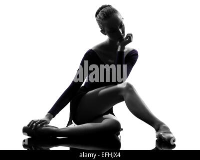 eine junge Frau Ballerina Ballett-Tänzerin, stretching Erwärmung oben im Silhouette Studio auf weißem Hintergrund Stockfoto