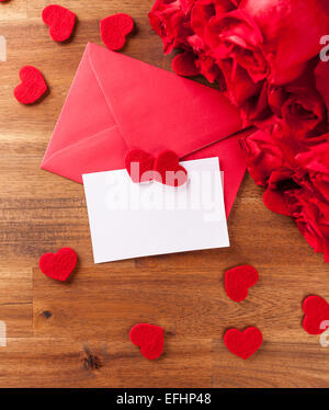 Strauß roter Rosen auf Holztisch mit roten Umschlag und leeres Papierkarte für text Stockfoto