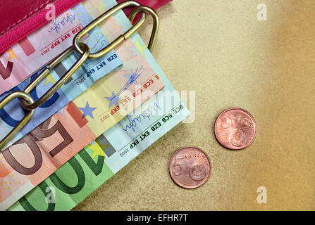 Geld in einer roten verkettete Brieftasche auf gelbem Hintergrund Stockfoto