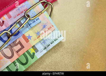 Geld in einer roten verkettete Brieftasche auf gelbem Hintergrund Stockfoto
