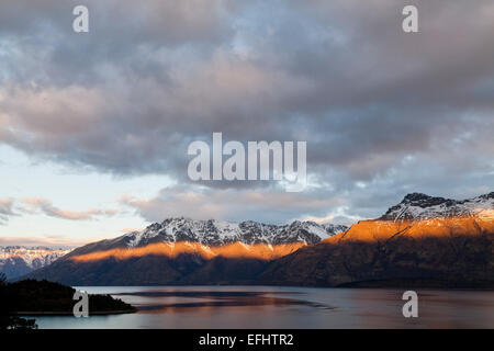 Lichtstrahl von der untergehenden Sonne auf Thomson Berge, Lake Wakatipu, Queenstown, Südinsel, Neuseeland Stockfoto