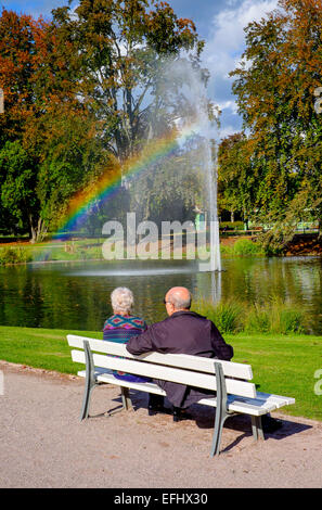 Ältere Paare auf der Werkbank, Wasserstrahl mit Regenbogen, Parc de l'Orangerie Park, Straßburg, Elsass, Frankreich, Europa Stockfoto