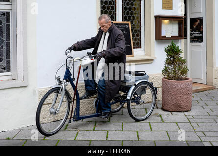 Älterer behinderter Mann, der ein Dreirad fährt Stockfoto