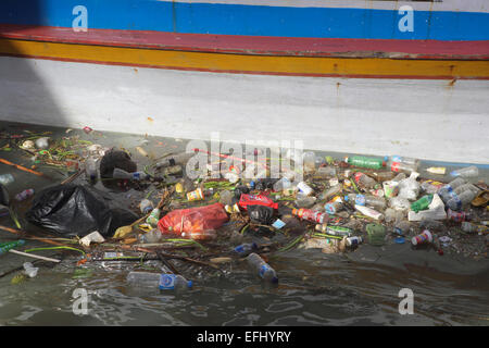 Kunststoff-Flaschen und anderen Müll schwebend in Manado River neben Holzboot Stockfoto