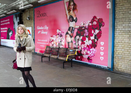 London, UK. 5. Februar 2015. Ein Pendler steht auf der Plattform an der Putney Bridge Station vor einem Riesenposter St Valentines Day am 14. Februar zu fördern. Bildnachweis: Amer Ghazzal/Alamy Live-Nachrichten Stockfoto