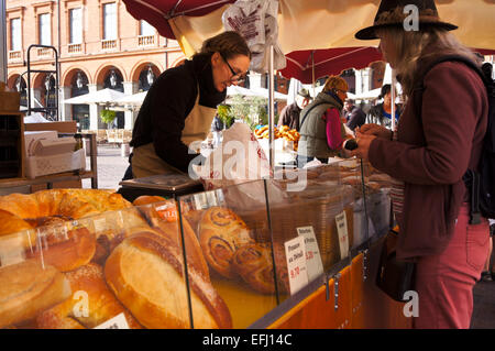 Eine Frau kauft Französische Brot zu einem Bauernmarkt, Place du Capitole, Toulouse, Haute-Garonne, Midi-Pyréneés, Royal, Frankreich Le Stockfoto