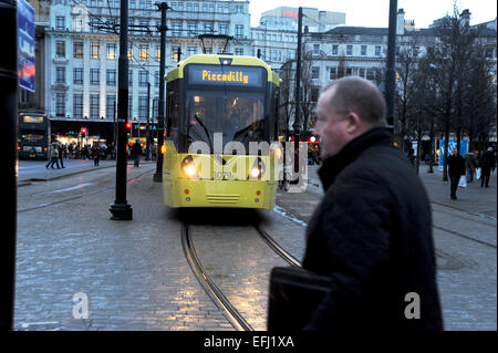 Manchester Lancashire UK - man überquert die Straße vor einer Straßenbahn im Stadtzentrum in Piccadilly Gardens Stockfoto