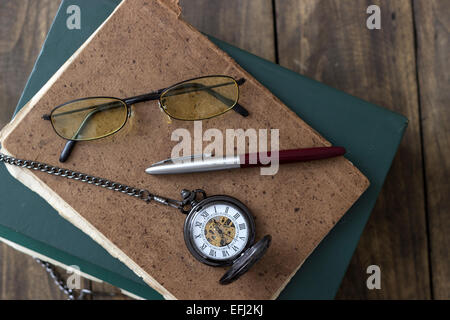 Eine antike Taschenuhr, Gläser und Bücher von oben Stockfoto