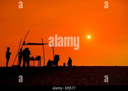 Menschen Silhoettes bei Sonnenuntergang am Strand Stockfoto