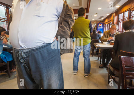 China, Shanghai, übergewichtigen Mannes Magen in einem Restaurant Stockfoto