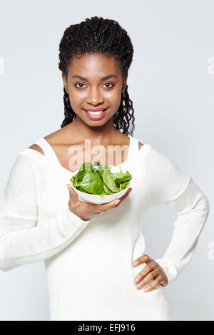 Porträt eines ethnischen Mädchens, der eine Schüssel Spinat hält Stockfoto