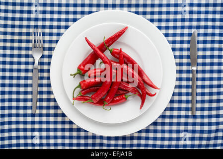 Rote Chilischoten auf einem karierten Tischdecke Stockfoto