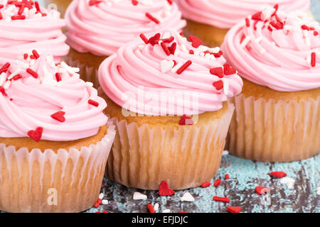 Rosa Valentinstag-Muffins mit Streuseln auf blau aus Holz-Vintage-Hintergrund Stockfoto