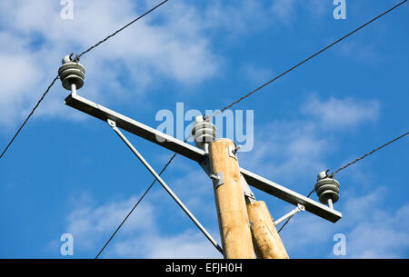 New wooden utility pole top with power line wires , cross arm and insulators against blue sky , Finland Stockfoto