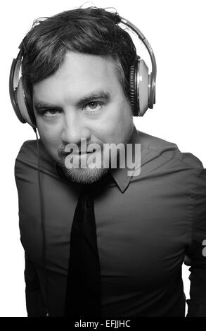 Kaukasischen Mann trägt graue Langarmhemd und Krawatte, die DJ-Style Kopfhörer anhören Stockfoto