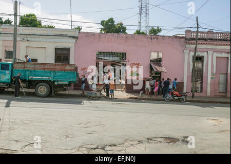 Kubanische Männer entladen frische Produkte aus einem Lieferwagen vor einem Markt mit vielen Kubaner Einkaufen in Cienfuegos, Kuba Stockfoto