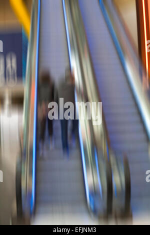 Abstrakte Unschärfe eines Paares, das im Februar in der O2-Arena am Peninsula Square in London UK die Rolltreppe hochfährt Stockfoto