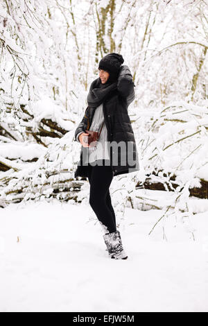 Lächelnde Brünette Frau im Winterwald Stockfoto