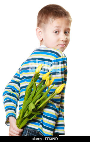 Urlaub Mutter Tag Konzept. Kleiner Junge hat Überraschungsgeschenk für Mama, gelbe Tulpen Blumen, hält es hinter dem Rücken Stockfoto