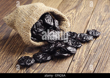 Getrocknete Pflaumen in kleine Sack auf alten Holztisch Stockfoto