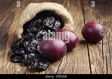 Pflaumen mit Pflaumen in kleine Sack auf alten Holztisch Stockfoto