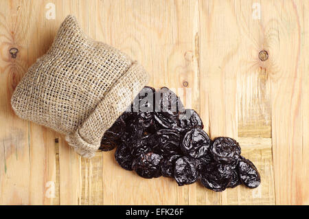 Pflaumen in kleine Sack auf hölzernen Hintergrund. Ansicht von oben Stockfoto