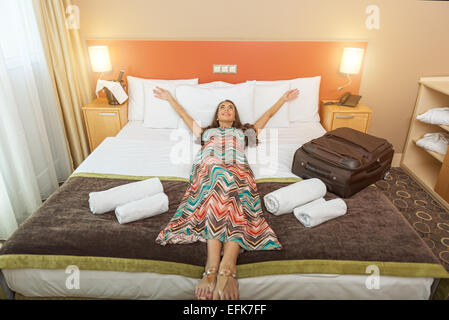 Junge Frau liegt im Bett eines Hotelzimmers Stockfoto