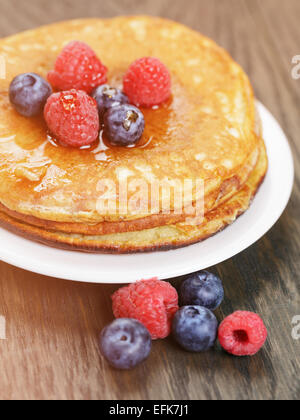 Pfannkuchen mit Beeren und Ahornsirup auf Holztisch Stockfoto